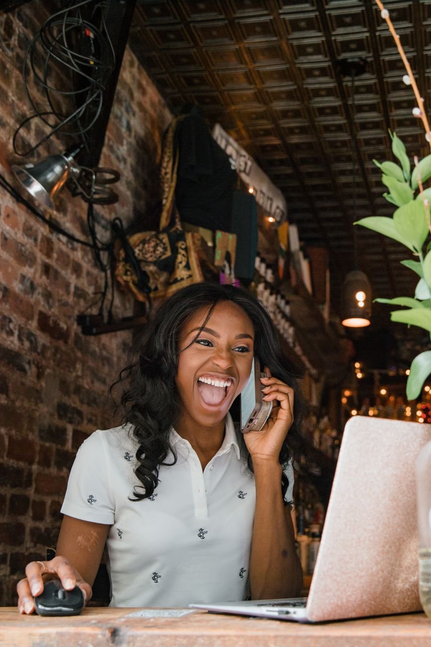 Excited small business owner laughing while talking on phone